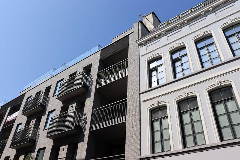 Fassade eines mehrstöckigen Gebäudes mit Balkonen und großen Fenstern unter blauem Himmel