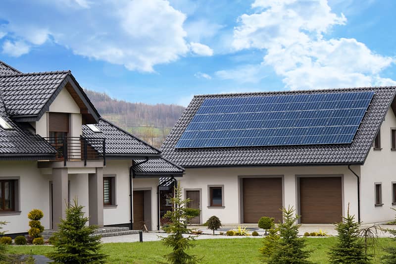 Zwei nebeneinanderstehende Einfamilienhäuser mit Solarpanelen auf den Dächern und gepflegtem Vorgarten